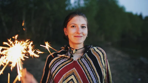 Portrait of young smiling woman with sparkler celebrating at beach party — Stock Photo, Image