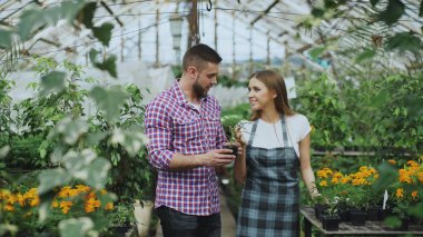 Müşteriye söz ve giving onu tavsiye Bahçe merkezinde çalışırken genç dostu kadın çiçekçi