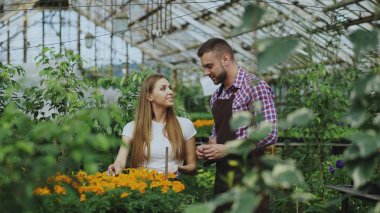 Genç neşeli müşteriye söz ve Bahçe merkezinde çalışırken tavsiyede çiçekçi adam