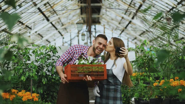 Vrolijke liefdevolle paar tuiniers maken selfie foto op smartphone camera terwijl u werkt in kas — Stockfoto