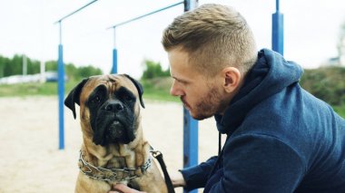 Sportif delikanlı sarılmak ve onun bullmastiff köpek doğa açık oyun