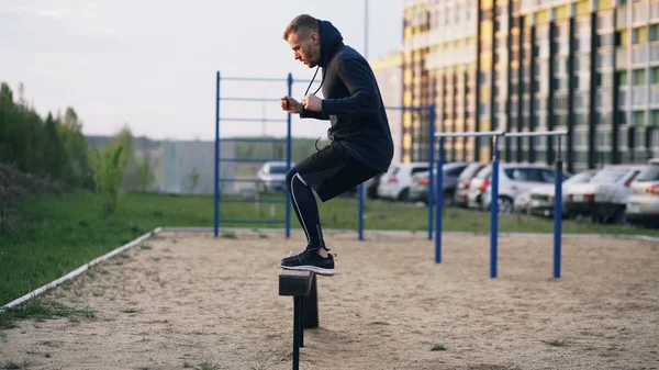 Przystojny mięśni młody człowiek ma Krzyś szkolenia skoków na bar w parku — Zdjęcie stockowe
