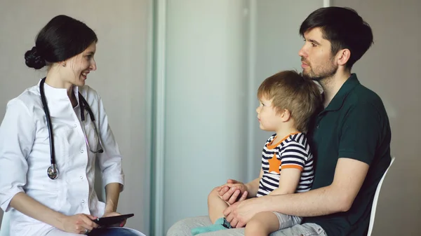 Mladá žena doktor mluvil s otcem malého chlapce v ordinaci — Stock fotografie