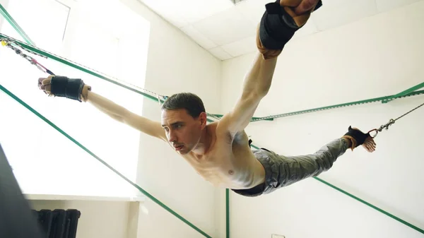 Joven haciendo ejercicio en cuartos de equipo de yoga y tirar de sus brazos y piernas con cuerdas —  Fotos de Stock