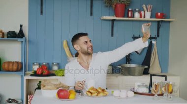 Neşeli genç adam selfie portre için Smartphone kullanarak süre var sabahları kahvaltı