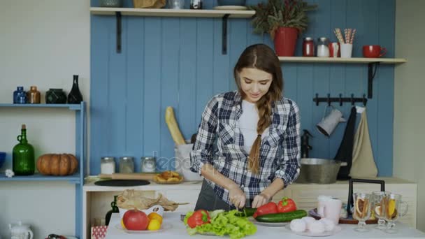 Vrolijke jonge grappige vrouw dansen en zingen tijdens het ontbijt koken in de keuken vroeg in de ochtend — Stockvideo