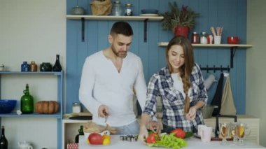 Mutlu genç çift mutfakta. Onun girfriend yemek çekici dans eden adam sabah ona yardım