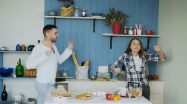 Genç ve neşeli çiftimiz evde kahvaltı masasını hazırlarken dans edip şarkı söylerken iyi eğlenceler.