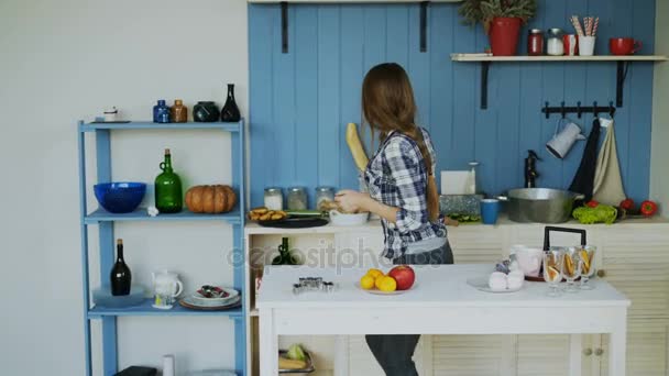 Wesoły młoda kobieta śmieszne, taniec i śpiew określone w tabeli na śniadanie w kuchni w domu — Wideo stockowe