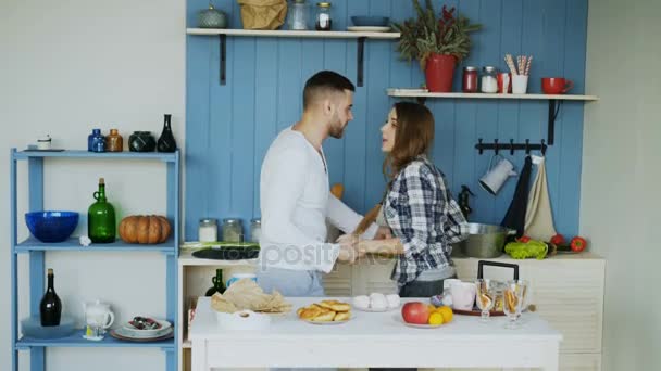 Joven pareja alegre se divierten bailando y cantando mientras ponen la mesa para el desayuno en la cocina en casa — Vídeo de stock