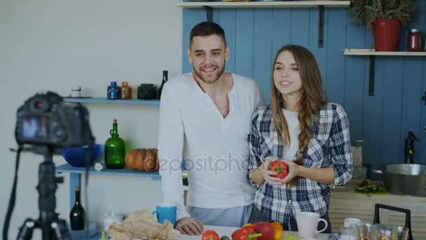 Cheerful attractive couple recording video food blog about cooking on dslr camera in the kitchen at home — Stock Video