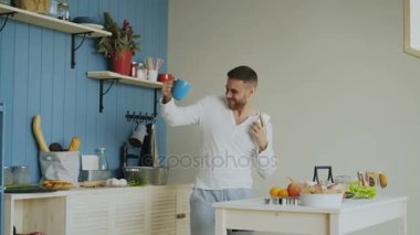 Dans ve sabahları evde onun smartphone kullanırken mutfakta şarkı neşeli mutlu adam