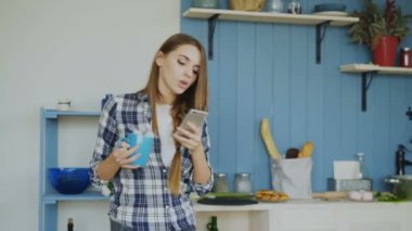 Mutfakta ise smartphone kullanarak ve evde sabah müzik şarkı ve dans çekici mutlu kız