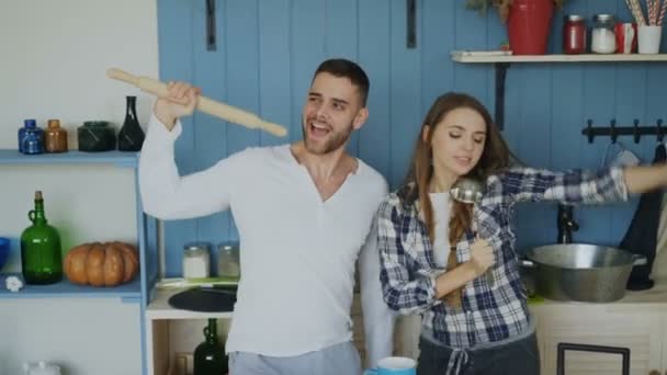 Fiatal örömteli pár szórakozni táncolni és énekelni, miközben megteríti az asztalt a reggelit a konyhában otthon — Stock videók