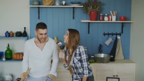 Junges fröhliches Paar hat Spaß beim Tanzen und Singen beim Frühstück in der heimischen Küche im Urlaub — Stockvideo
