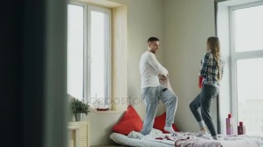 Mutlu ve sevgi dolu bir genç çift yatakta evde yastıklar sabahları mücadele.