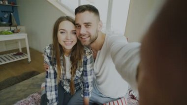 POV shot tatlı ve sevgi dolu çift smartphone holding ve sabah evde yatakta oturan arkadaşlar sohbet video sohbet söz