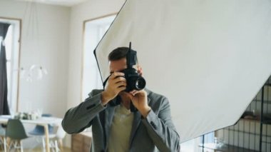 Genç adam fotoğrafçı çekim modelinin dijital kamerada fotoğraf stüdyosu çalışma
