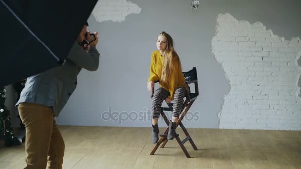 Joven hermosa mujer modelo posando para el fotógrafo, mientras que él está disparando con una cámara digital en el estudio de fotos en el interior — Vídeo de stock