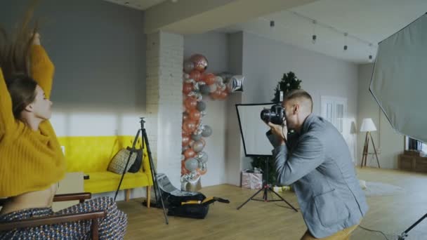 Fotógrafo profissional homem tirando foto de menina modelo bonita com câmera digital em estúdio — Vídeo de Stock