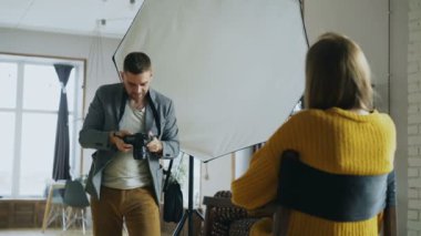 Genç güzel kadın model bir dijital kamera ile fotoğraf stüdyosu kapalı çekerken fotoğrafçı adam için poz