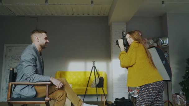 Fotógrafo profesional mujer tomando fotos de hombre de negocios modelo chica con cámara digital en el estudio — Vídeos de Stock