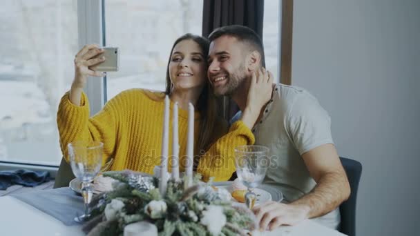 Щаслива усміхнена пара обідає і знімає портрет селфі зі смартфоном у кафе в приміщенні — стокове відео