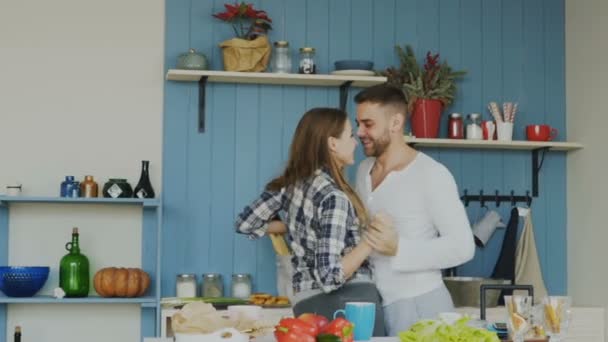 Веселая и привлекательная молодая пара влюбленных танцует вместе на кухне дома по праздникам — стоковое видео