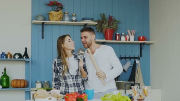 Evde mutfakta yemek yaparken şarkı ve dans eğlenceli genç Slowmotion neşeli çift var — Stok video