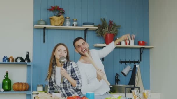 Slowmotion of Young joyful couple have fun dancing and singing while cooking in the kitchen at home — Stock Video