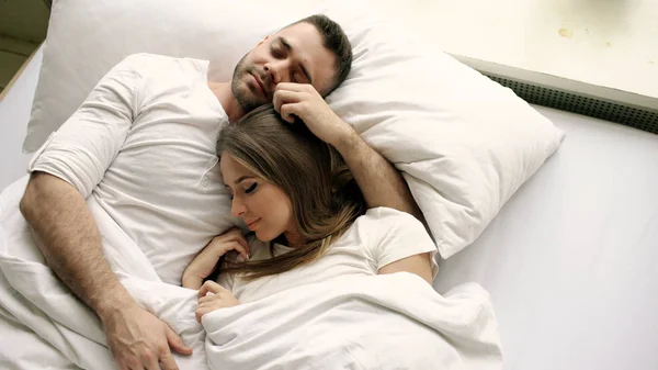 Jovem casal bonito e amoroso beijar e abraçar na cama enquanto acorda de manhã. Visão superior de homem atraente beijando e falando sua esposa sorridente — Fotografia de Stock