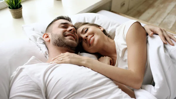 Close-up de jovem linda e amorosa conversa casal e abraço na cama enquanto acorda de manhã . — Fotografia de Stock