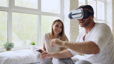 Tablet bilgisayar ve sanal gerçeklik kulaklık evde yatakta otururken 360 Vr video oyun oynarken ile genç şirin çift