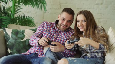 Mutlu ve sevgi dolu bir genç çift gamepad konsol oyun ve eğlenceli evde oturma odasında kanepede oturan