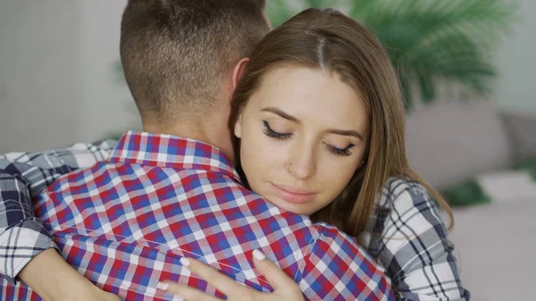 Closeup of young upset couple embrace each other after quarrel. Woman looking wistful and sad hug her boyfrined at home — Stock Photo, Image