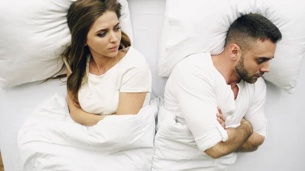 Top view of young upset couple lying in bed have problems after quarrel and angry each other at home — Stock Photo, Image