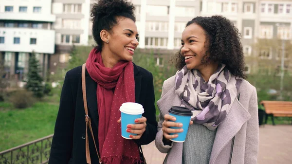 Дві красиві змішані раси друзі п'ють каву і розмовляють після шопінгу і прогулянки по міській вулиці — стокове фото