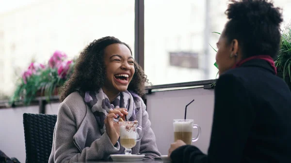 İki çekici konuşan ve içme kahve sokak Cafe yarış bayanlar karışık. Arkadaşlar alışveriş merkezi satış ziyaret ettikten sonra iyi eğlenceler — Stok fotoğraf