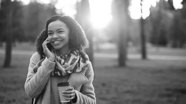 Ελκυστική μικτή φυλή κορίτσι μιλάμε smartphone και να πίνει καφέ στο πάρκο της πόλης με Τσάντες. Νεαρή γυναίκα μετά από ψώνια στο εμπορικό κέντρο πώλησης — Φωτογραφία Αρχείου