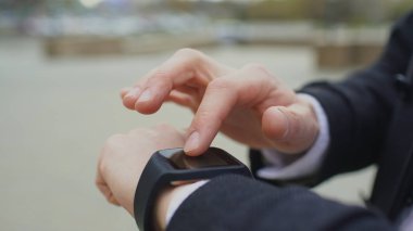 Onun smartwatch dokunmatik ekran ayakta sokakta kullanarak iş adamı ele closeup