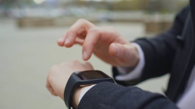 Onun smartwatch dokunmatik ekran ayakta sokakta kullanarak iş adamı ele closeup
