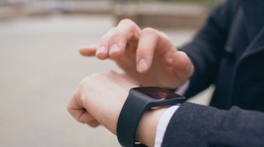 Onun smartwatch dokunmatik ekran ayakta sokakta kullanarak iş adamı ele closeup