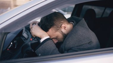Young bearded business man sitting in car very upset and stressed after hard failure and moving in traffic jam clipart