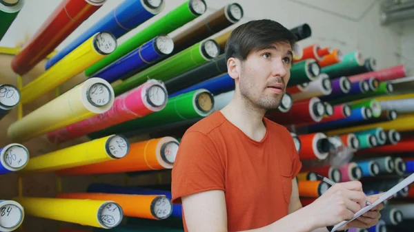 Jeune travailleur dans un entrepôt avec presse-papiers vérifier l'inventaire. Homme travaille dans le département des ventes de matériel publicitaire — Photo