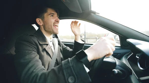 Gelukkig knappe zakenman rijdende auto en zingen. Man is blij na het maken van deals en stations home — Stockfoto