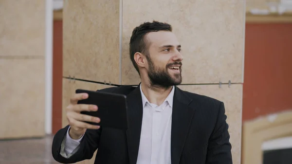 Joven hombre de negocios hablando en la tableta de chat de vídeo con su esposa. Hombre de negocios que utiliza la aplicación para tener una conversación de videoconferencia con su familia durante el descanso — Foto de Stock