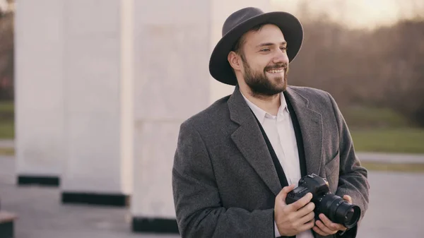 Elegantní mladý fotograf muž v klobouku stál venku a fotografování turistických zajímavostí během cestování — Stock fotografie