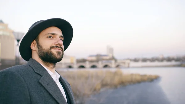 Şapkanı ve Paltonu cityscape izliyor ve Riverside'da dururken hayal turist adam genç sakallı — Stok fotoğraf