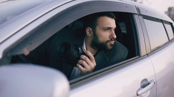 Detektif muda duduk di dalam mobil dan memotret dengan kamera dslr — Stok Foto