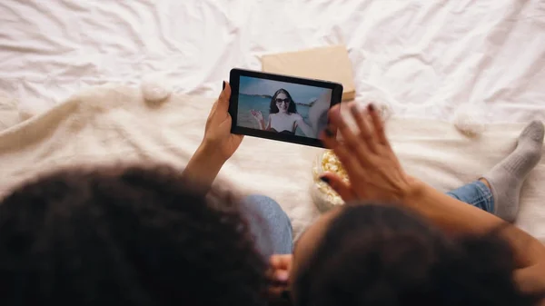 Két barátnő ül ágyas otthon felülnézete a skype-ra tabletta számítógép beszélgetett a barátja, miután nyaralás a strandon — Stock Fotó